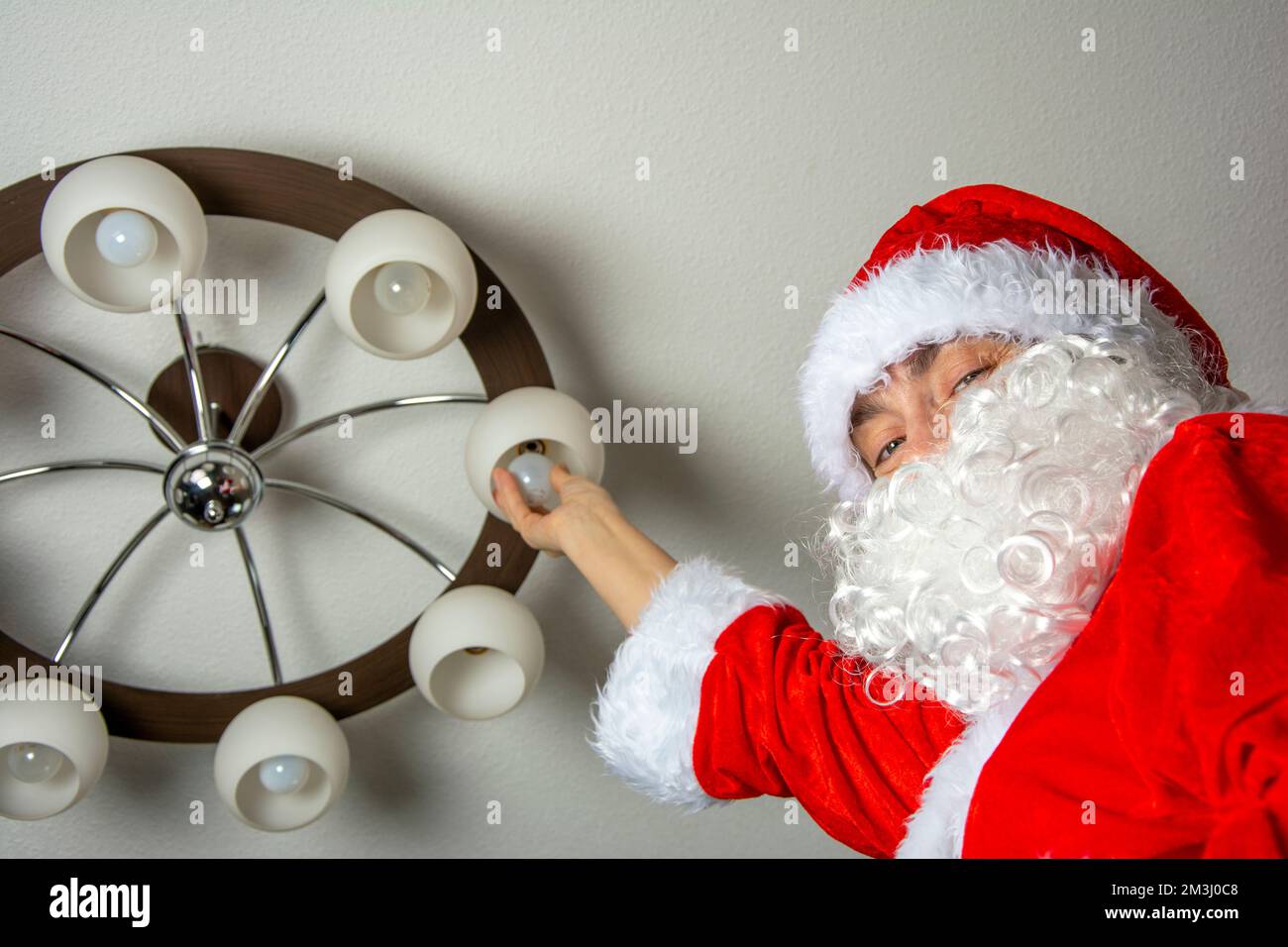 Babbo Natale cambia le lampadine bruciate nel lampadario Foto Stock
