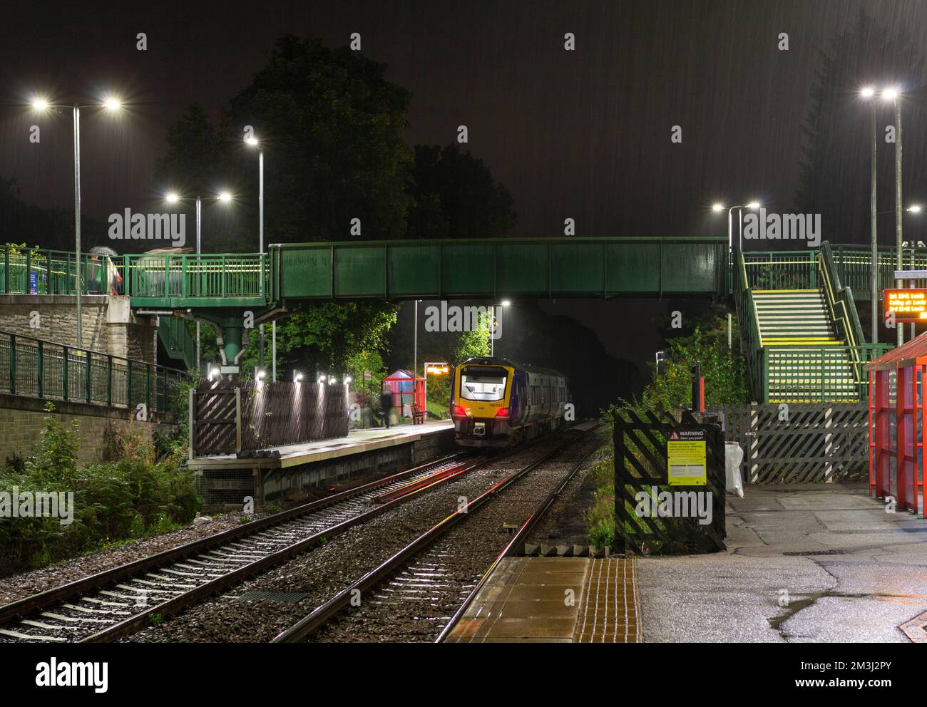Stazione ferroviaria di Woodlesford, Yorkshire, Regno Unito. Un treno di classe 195 della ferrovia del Nord chiama in una notte bagnata al buio Foto Stock