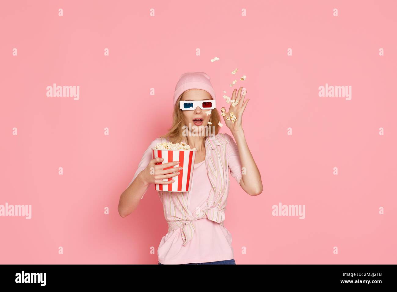 ragazza terrorizzata guardando film horror , tenendo un secchio di popcorn Foto Stock