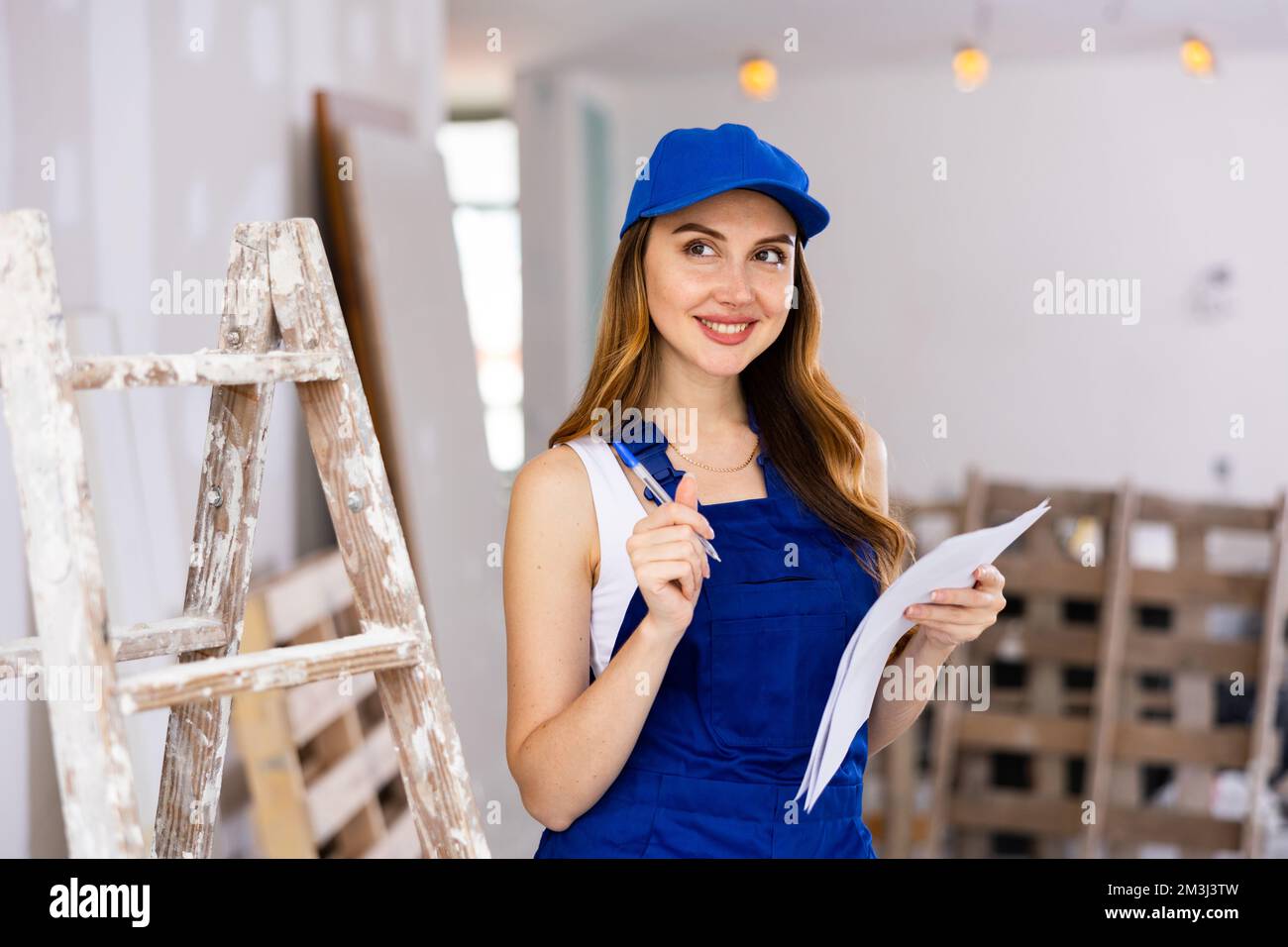 Costruttore donna sorridente appaltatore con carte in cantiere Foto Stock