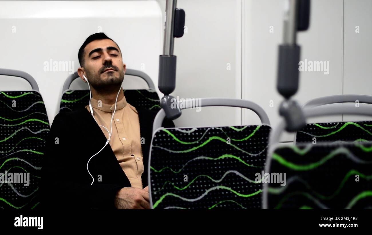 Un bell'uomo che ballava nei trasporti. Motion.A elegante uomo d'affari che va a lavorare in un autobus vuoto ascoltando la musica con le cuffie. Fu di alta qualità Foto Stock