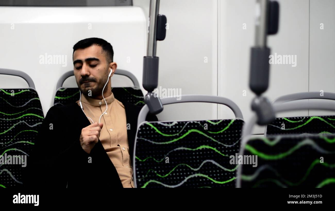 Un bell'uomo che ballava nei trasporti. Motion.A elegante uomo d'affari che va a lavorare in un autobus vuoto ascoltando la musica con le cuffie. Fu di alta qualità Foto Stock