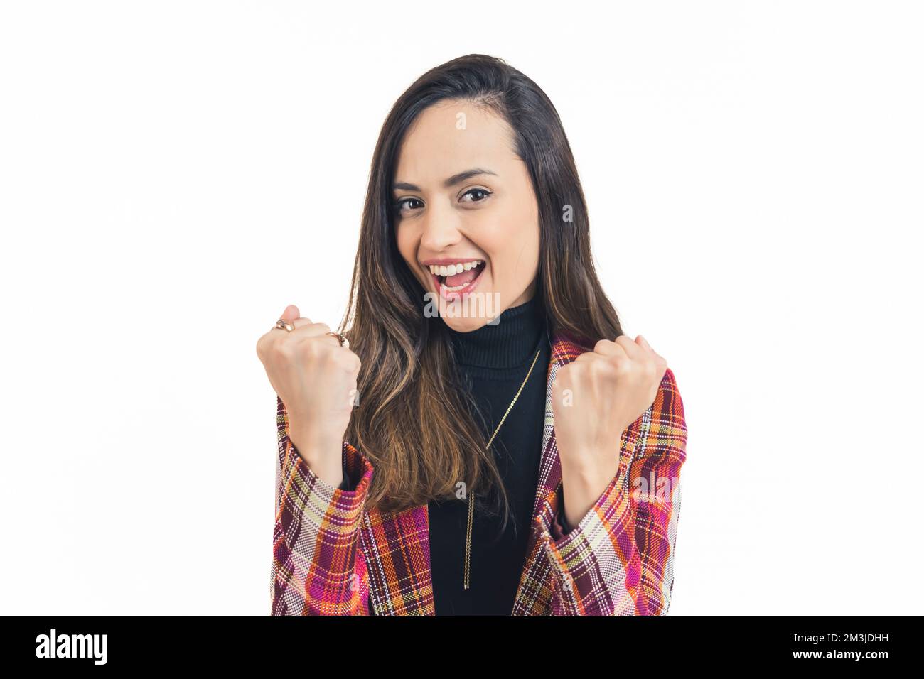 Ritratto di giovane donna latino-americana con coloratissimo blazer guardando in fotocamera sorridente con entrambi i pugni fino gesturing successo. Sfondo bianco copia spazio orizzontale studio shot. Foto di alta qualità Foto Stock