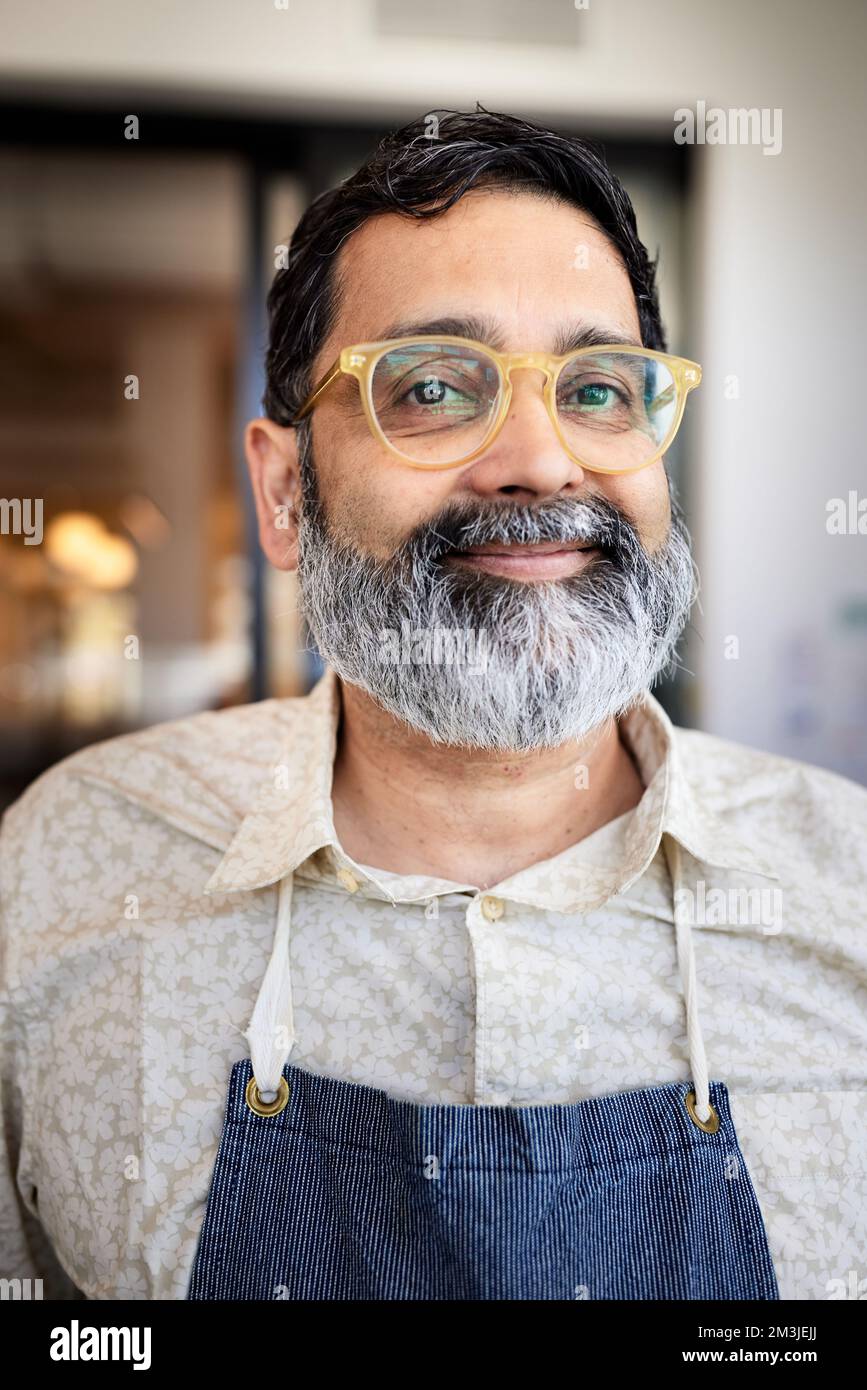Ritratto di sorridente proprietario di caffetteria con barba e occhiali Foto Stock