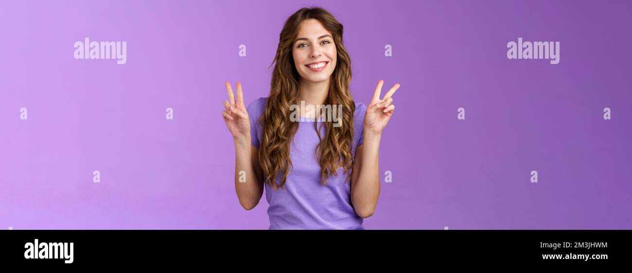 Amici di pace. Rilassato amichevole carino auto-assicurato ragazza lungo ricciolo acconciatura segno di vittoria sorridente ampiamente allegro espresso positivo ottimista Foto Stock