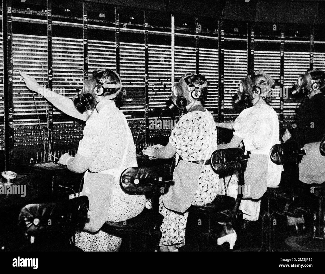 Operatori di quadri di controllo a Faraday Building, City, London, che indossano speciali maschere a gas con auricolari e boccagli; una misura precauzionale anti-aria-raid in caso di attacco di gas. 1938 Foto Stock