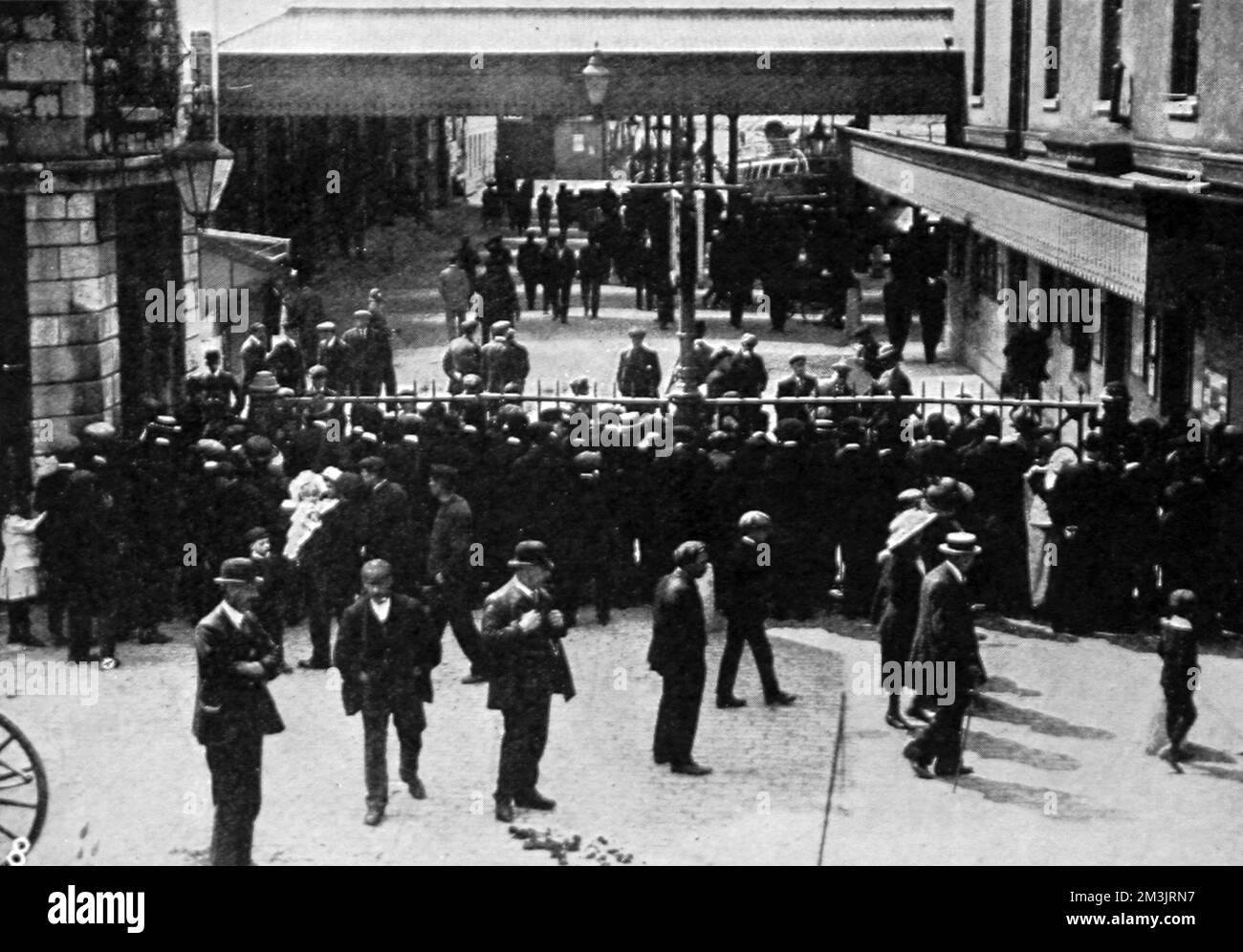 Vista della folla che guarda attraverso le porte chiuse ai moli di Plymouth mentre i sopravvissuti del disastro sono tornati nel Regno Unito. Data: 1912 Foto Stock