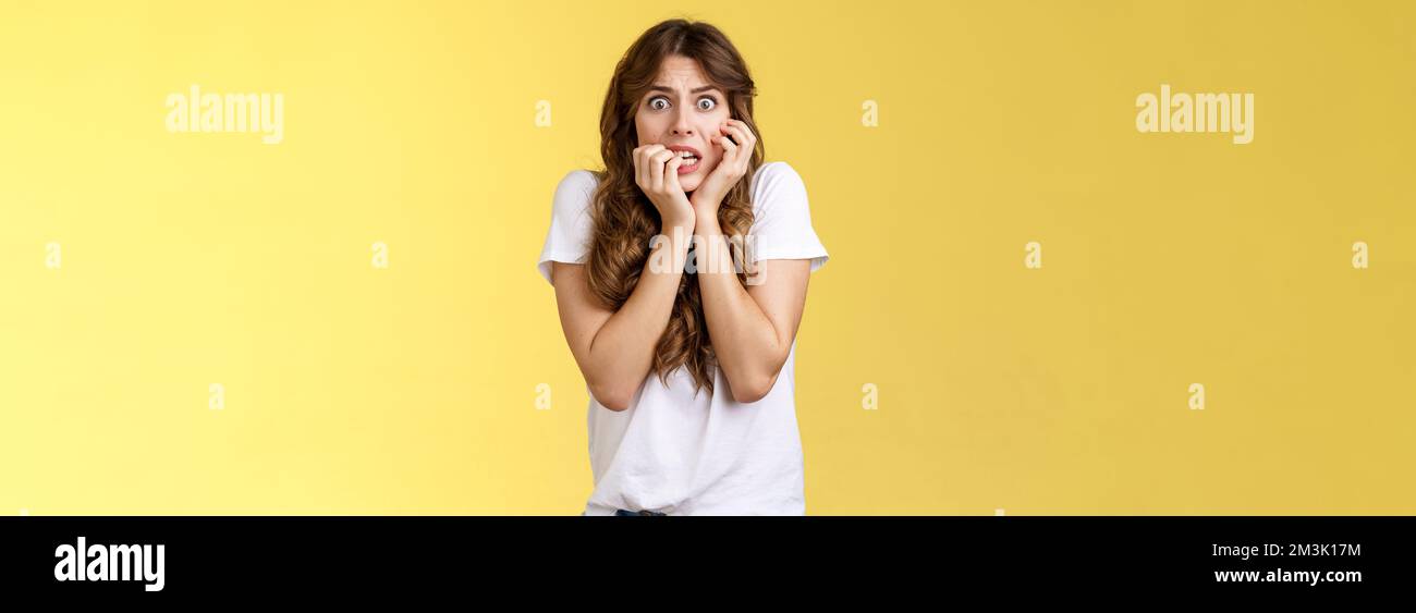 Ragazza sensazione di panico paura timido insicuro morso unghie stare fotocamera spaventato clench denti tremante paura toccare faccia nervosamente sensazione Foto Stock