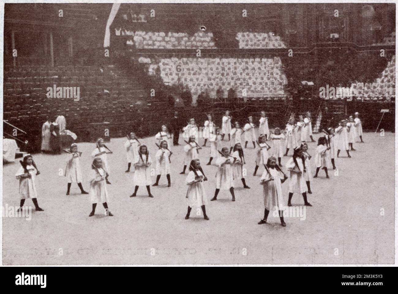 Scena dalle celebrazioni annuali delle case del Dr. Barnardo nella Royal Albert Hall. Qui le ragazze giovani eseguono l'esercitazione fisica nel randello indiano che mostra. Ogni anno nella Sala Albert è stata allestita una mostra del buon lavoro delle Case del Dott. Barnardo. Thomas John Barnardo (1845-1905) è una figura classica vittoriana, evangelica, imprenditoriale e filantropica. La sua crociata per 'scudere i bambini dalle strade' fu uno degli interventi sociali più conosciuti nell'ultima metà del XIX secolo. Foto Stock