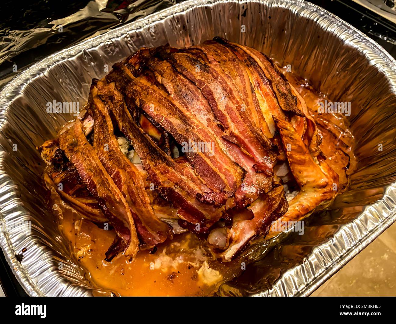 Tacchino avvolto in pancetta. tacchino rivestito con pancetta per il giorno del Ringraziamento in un piatto di alluminio. Foto Stock