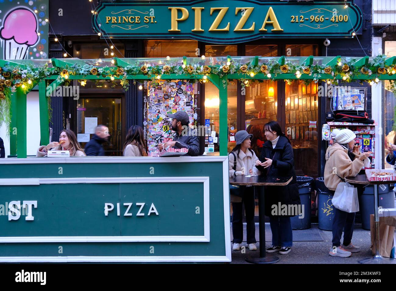 I clienti che gustano pizze fuori dal popolare Prince Street Pizza nel quartiere di Nolita.Manhattan.New York City.USA Foto Stock