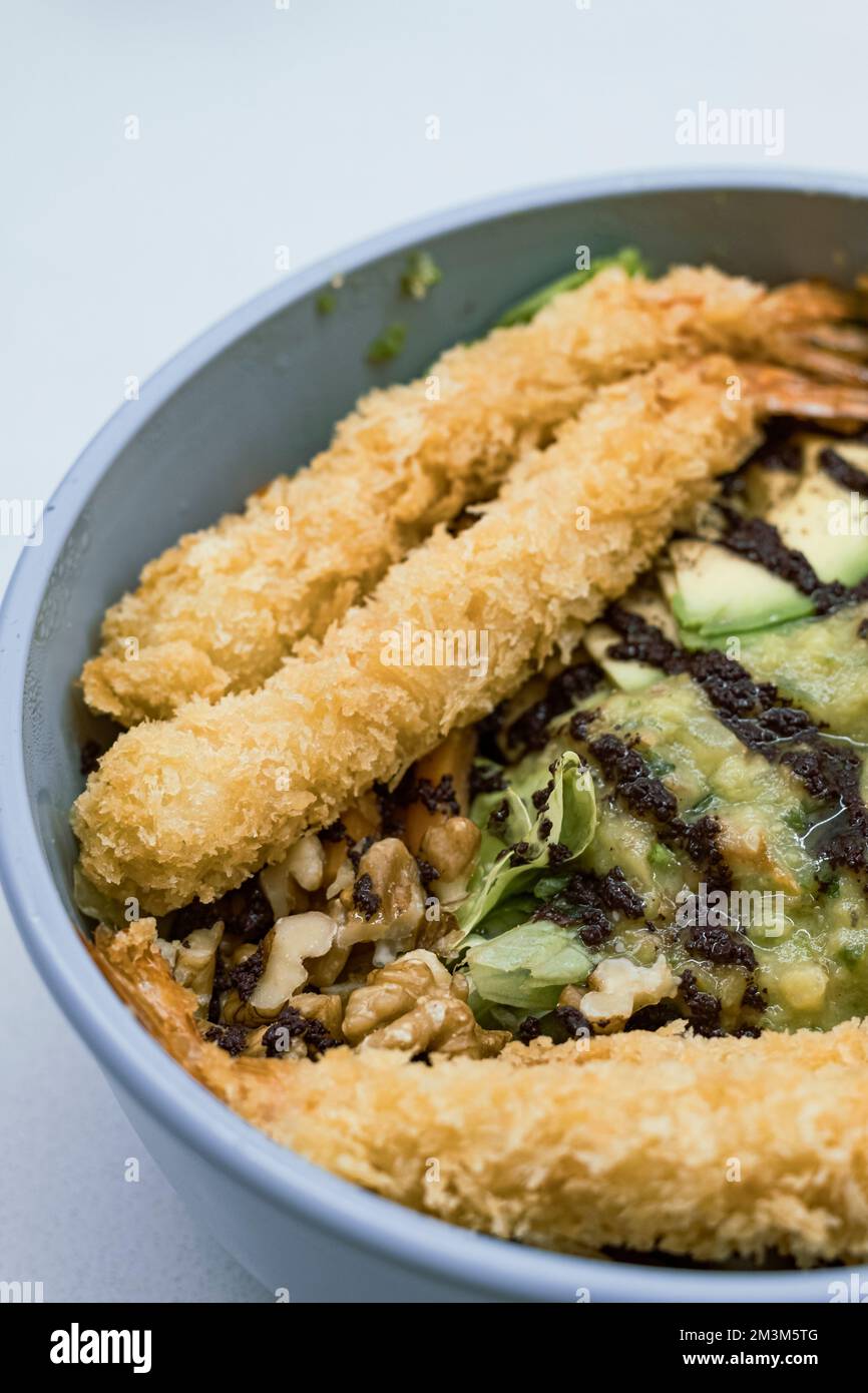 Pesce impanato su una ciotola blu di verdure con avocado su un brunch sano e gustoso vicino ancora Foto Stock