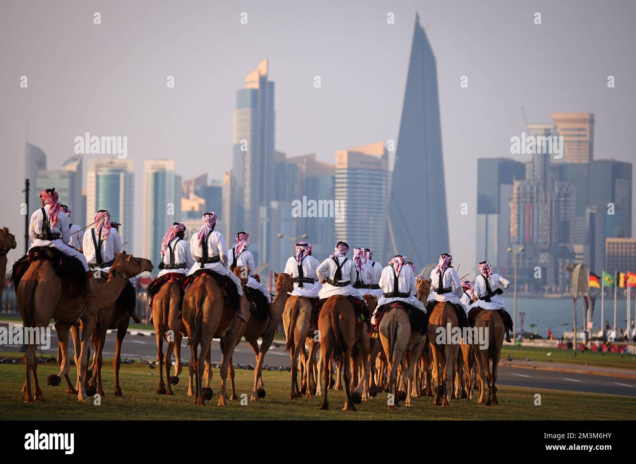 Sicherheitskräfte mit ihren Kamelen auf einer Wiese vor dem Amiri Diwan, dem officiellen Arbeitsplatz und das Büro des Emirs des Staates Katar im Hintergrund die Skyline of Doha West Bay mit den modernen Hochhäusern forze di sicurezza con i loro cammelli su un prato di fronte all'Amiri Diwan, Il luogo di lavoro ufficiale e l'ufficio dell'Emiro dello Stato del Qatar, sullo sfondo lo skyline di Doha West Bay con i moderni e alti edifici Fussball WM 2022 in Qatar FIFA Football World Cup 2022 © diebilderwelt / Alamy Stock Foto Stock