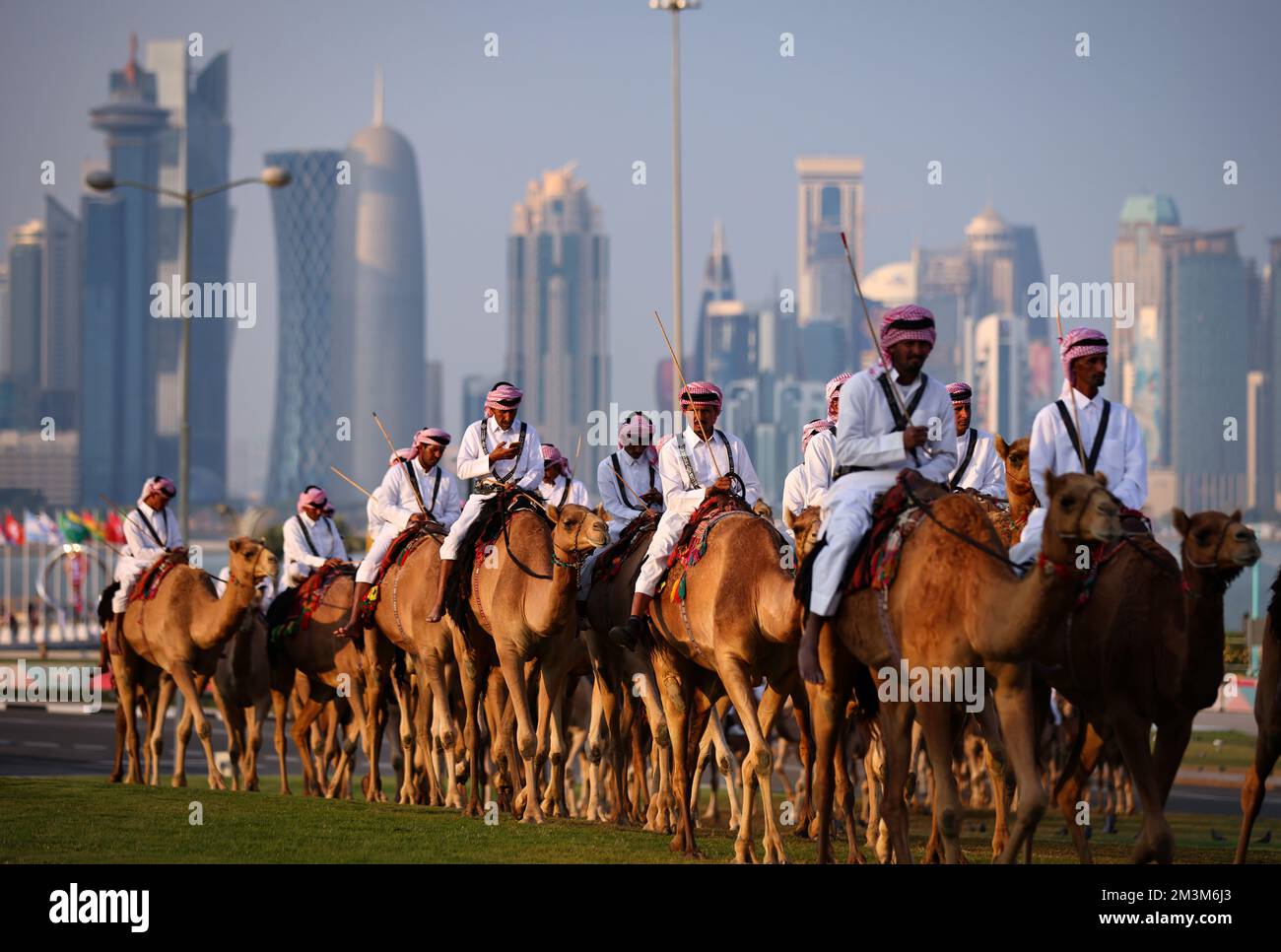 Sicherheitskräfte mit ihren Kamelen auf einer Wiese vor dem Amiri Diwan, dem officiellen Arbeitsplatz und das Büro des Emirs des Staates Katar im Hintergrund die Skyline of Doha West Bay mit den modernen Hochhäusern forze di sicurezza con i loro cammelli su un prato di fronte all'Amiri Diwan, Il luogo di lavoro ufficiale e l'ufficio dell'Emiro dello Stato del Qatar, sullo sfondo lo skyline di Doha West Bay con i moderni e alti edifici Fussball WM 2022 in Qatar FIFA Football World Cup 2022 © diebilderwelt / Alamy Stock Foto Stock