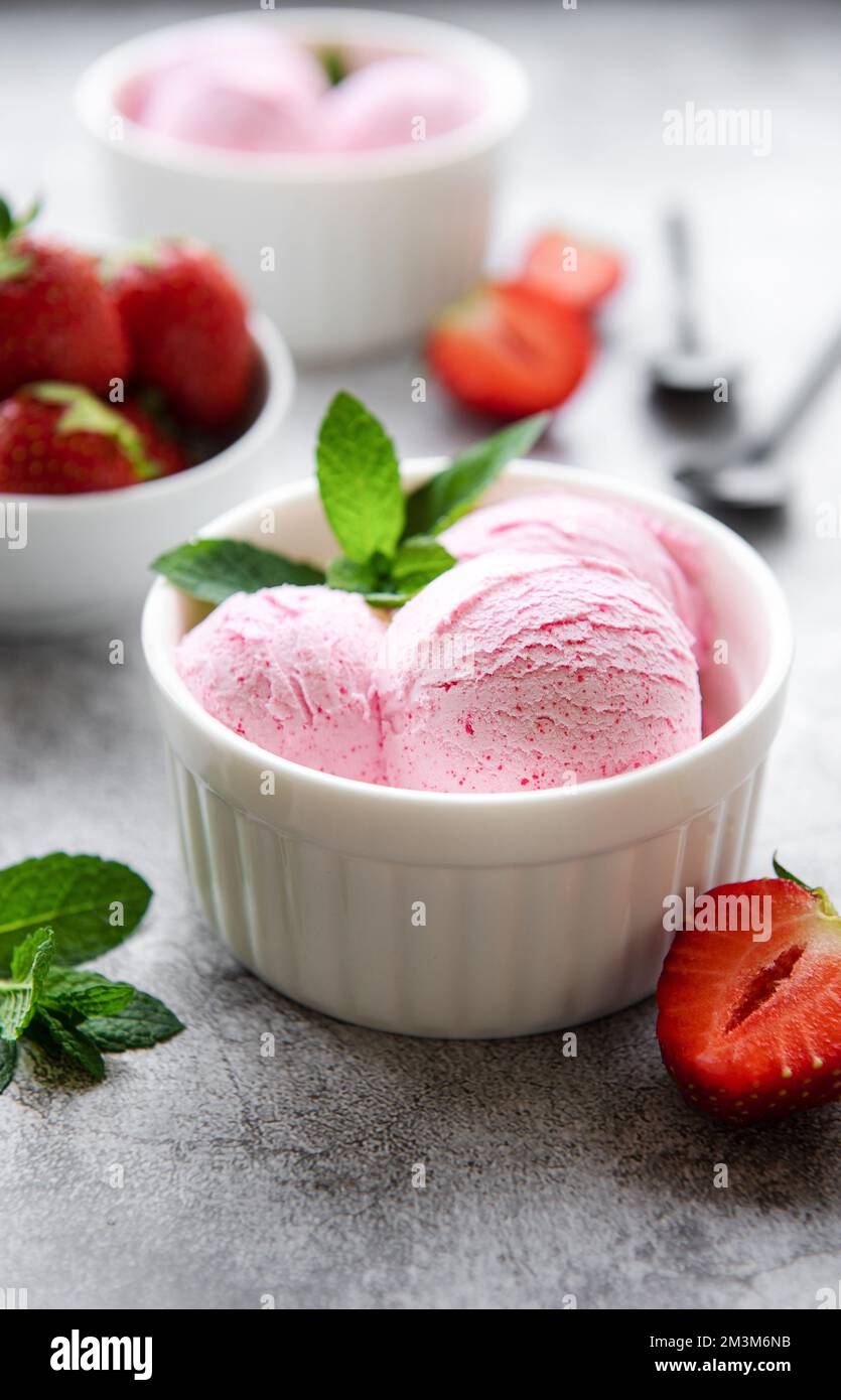 Gelato alla fragola fatto in casa con fragole fresche. Dolce bacche dessert estate. Sfondo concreto Foto Stock