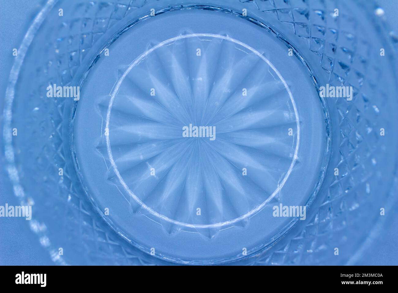 Macro struttura astratta sfondo di una superficie rotonda in vetro cristallo con un design sunburst circondato da tagli di diamante, nel colore del blu chiaro Foto Stock