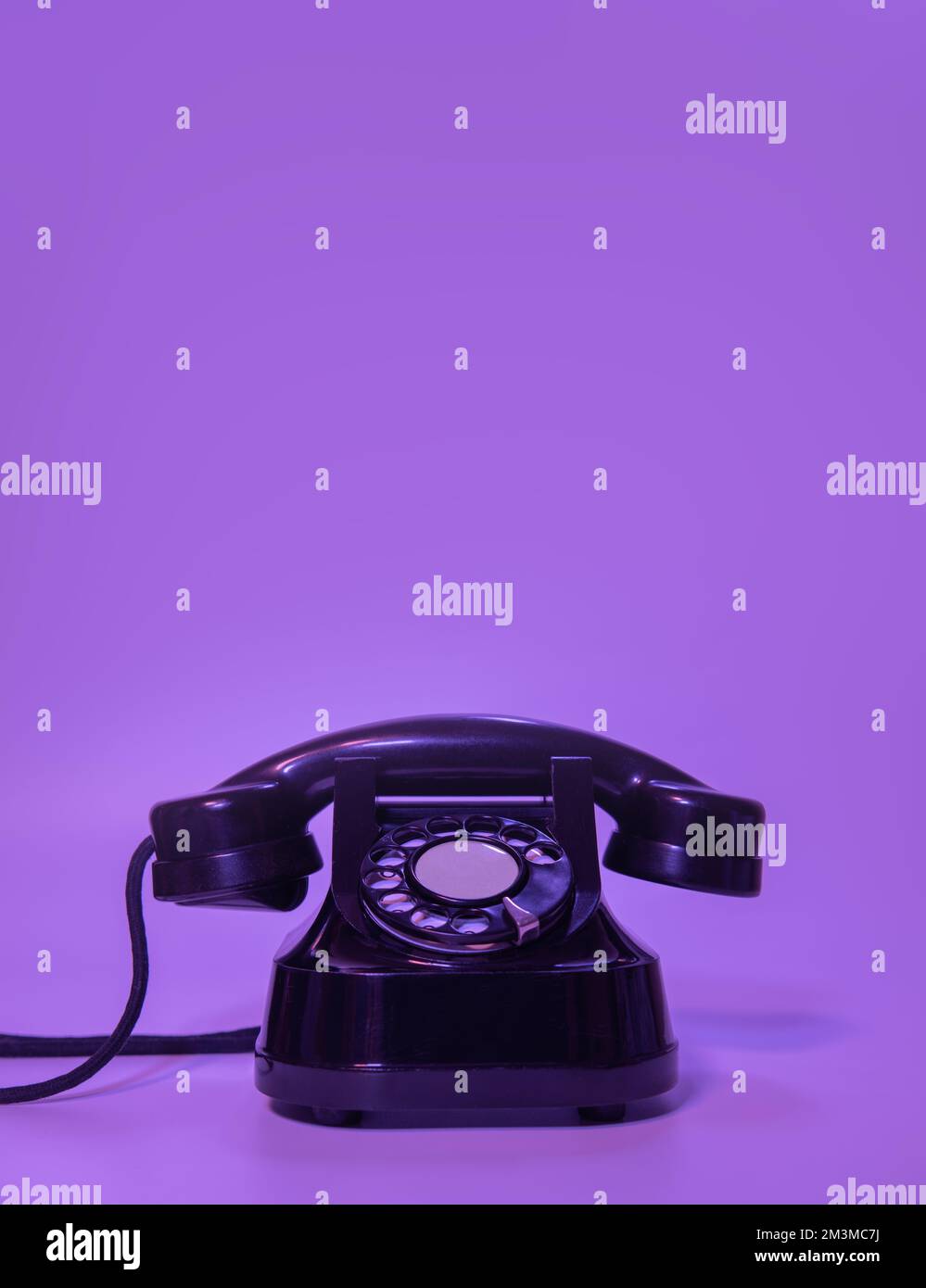 vecchio telefono nero su sfondo viola. Foto Stock