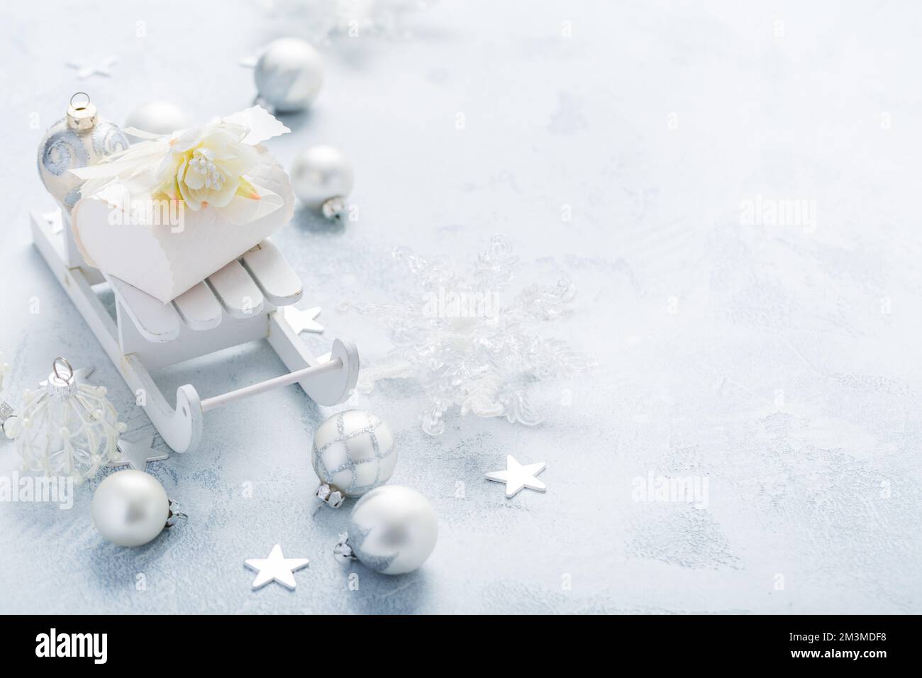 Ornamenti natalizi, palle e piccolo cofanetto su slitta in argento e bianco nevoso Foto Stock