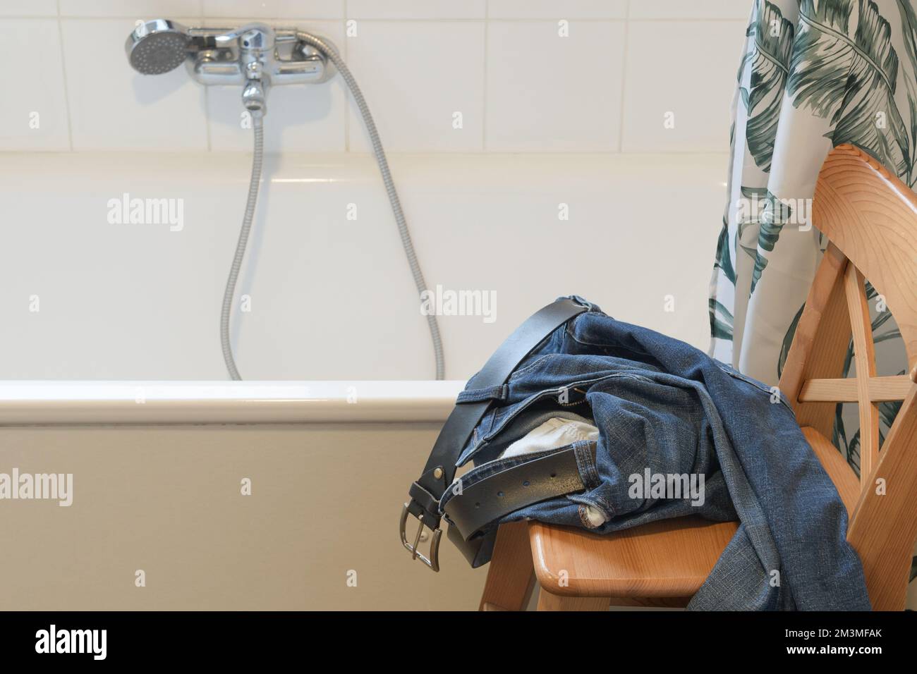 Togliere i jeans in bagno prima di una doccia. Foto Stock