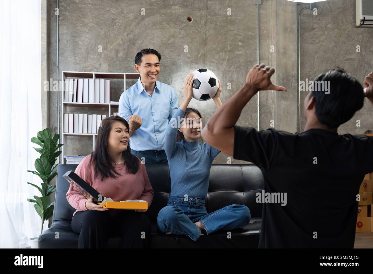 Gli amici guardano gli sport in TV, festeggiano e festeggiano. Felici tifosi diversi amici asiatici sedersi sul divano con popcorn e bevande Foto Stock