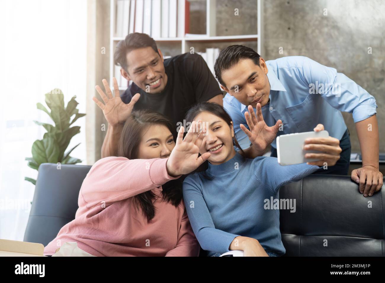 Gli amici guardano gli sport in TV, festeggiano e festeggiano. Felici tifosi diversi amici asiatici sedersi sul divano con popcorn e bevande Foto Stock