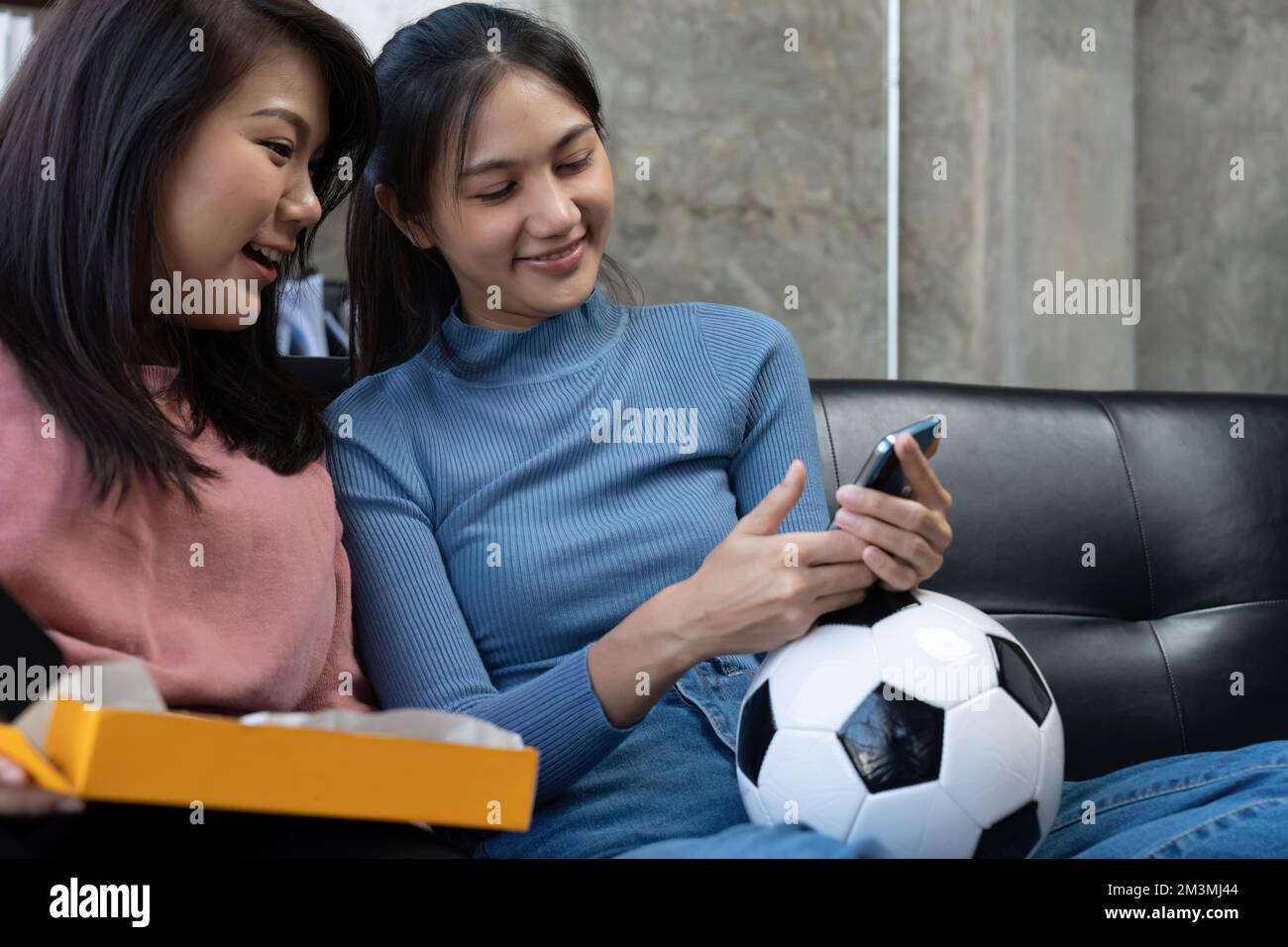 Gli amici guardano gli sport sul telefono cellulare, festeggiano e festeggiano. Felici tifosi diversi amici asiatici sedersi sul divano con popcorn e bevande Foto Stock