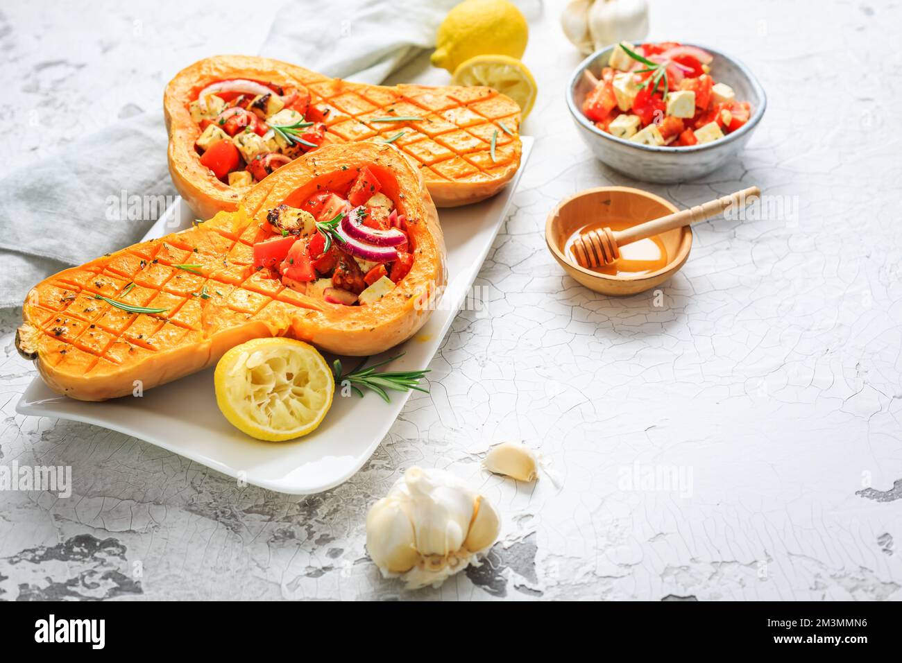 Zucca arrosto a metà con farcitura di verdure piccanti e formaggio feta Foto Stock