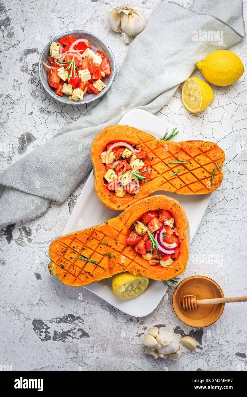 Zucca arrosto a metà con farcitura di verdure piccanti e formaggio feta Foto Stock