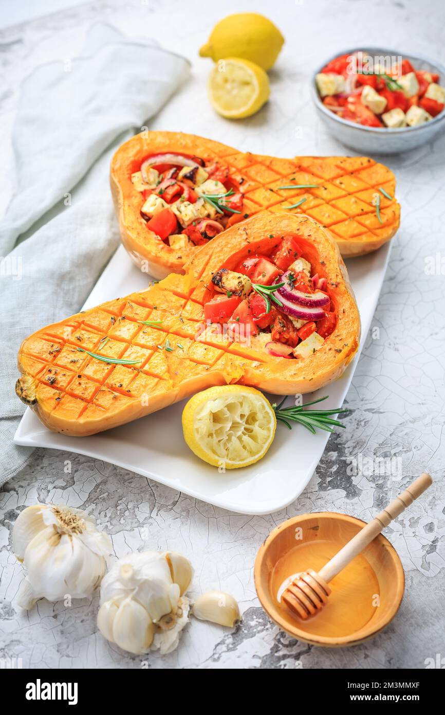 Zucca arrosto a metà con farcitura di verdure piccanti e formaggio feta Foto Stock