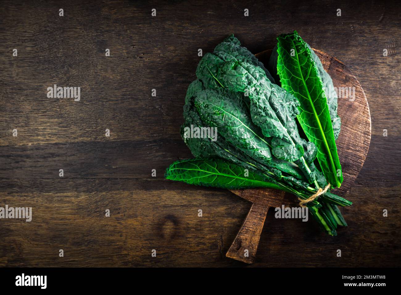 Cavolo nero, cavolo nero, cavolo nero riccio. Nero di Toscana (Brassica oleracea) sul tagliere Foto Stock