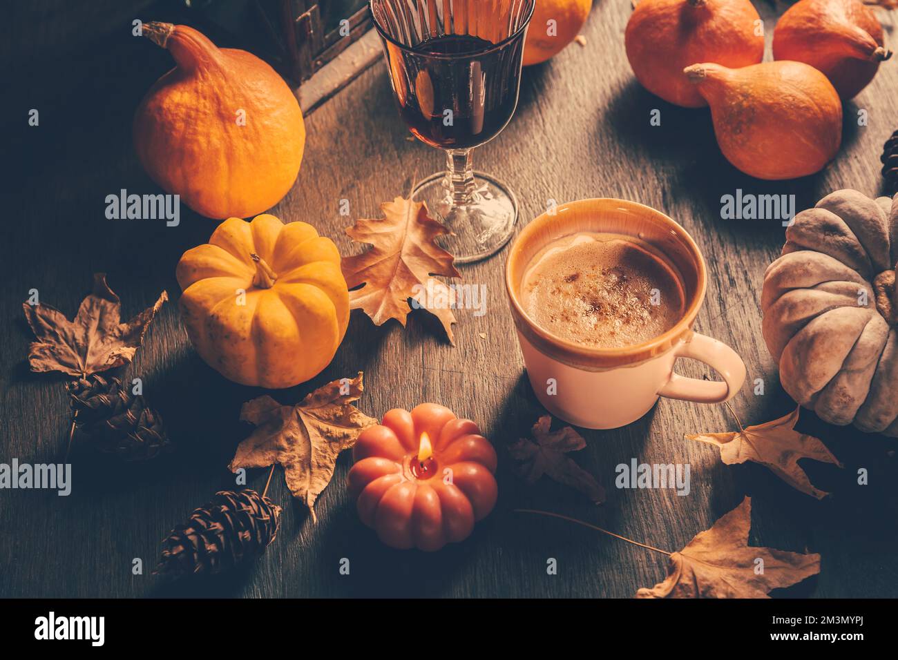 Accogliente composizione autunnale. Cioccolata calda con foglie autunnali e zucche sul tavolo da cucina Foto Stock