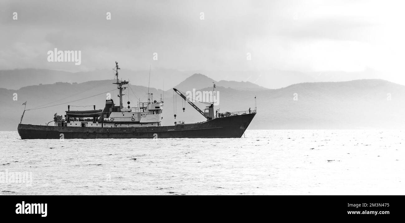 Il grande peschereccio sullo sfondo di colline e vulcani Foto Stock
