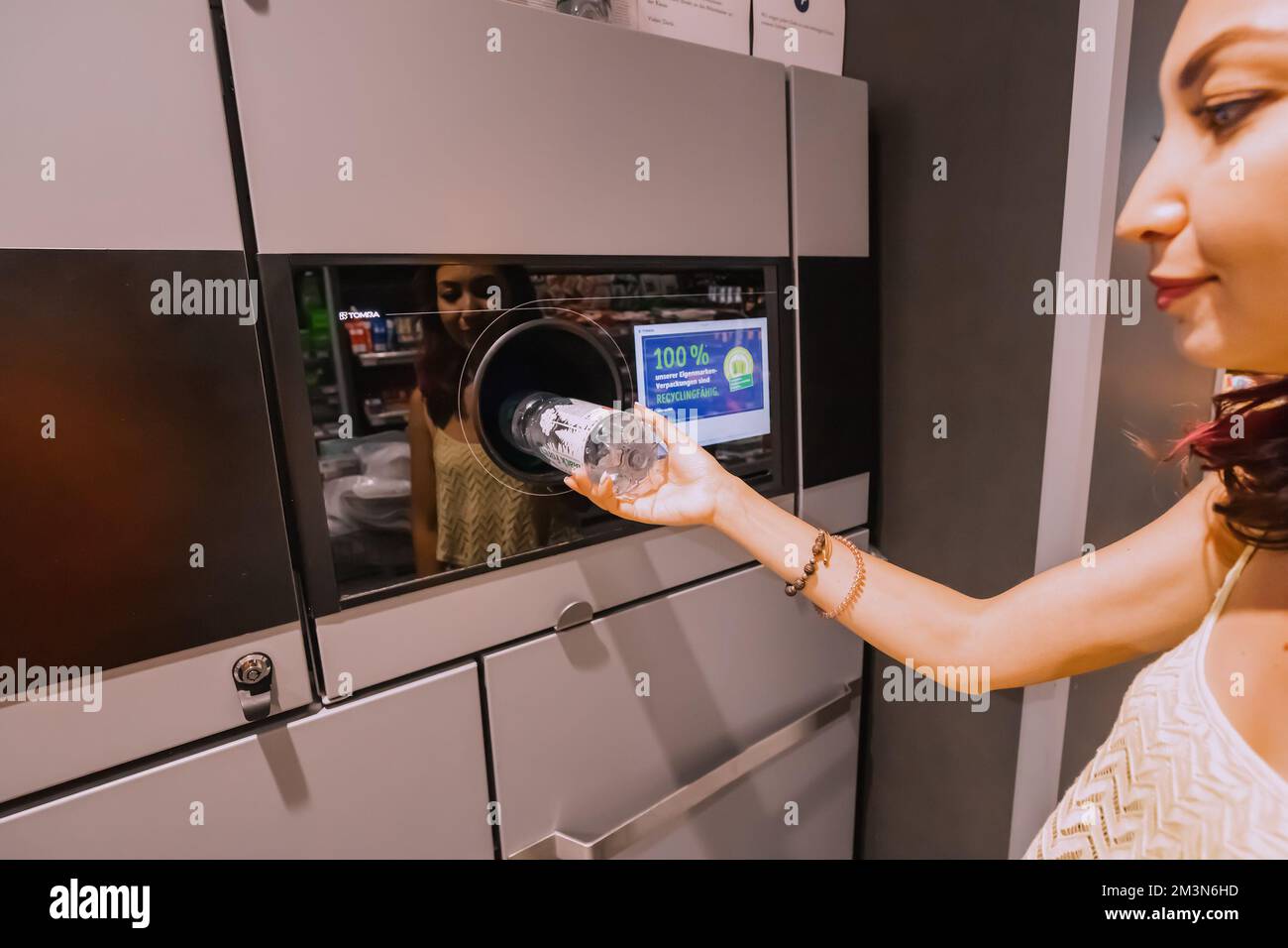 30 luglio 2022, Colonia, Germania: Una studentessa consegna una bottiglia di plastica per il riciclaggio alla macchina automatica. Stile di vita ecocompatibile e cas Foto Stock