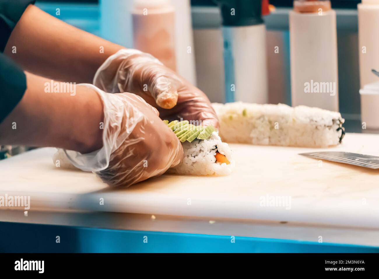 Lo chef si mette a disposizione dei guanti per cucinare i sushi al ristorante Foto Stock