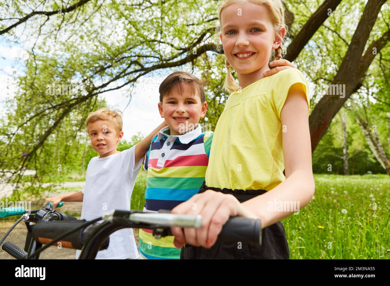 Ritratto di amici multirazziali sorridenti con le braccia l'una intorno all'altra in piedi nel parco Foto Stock