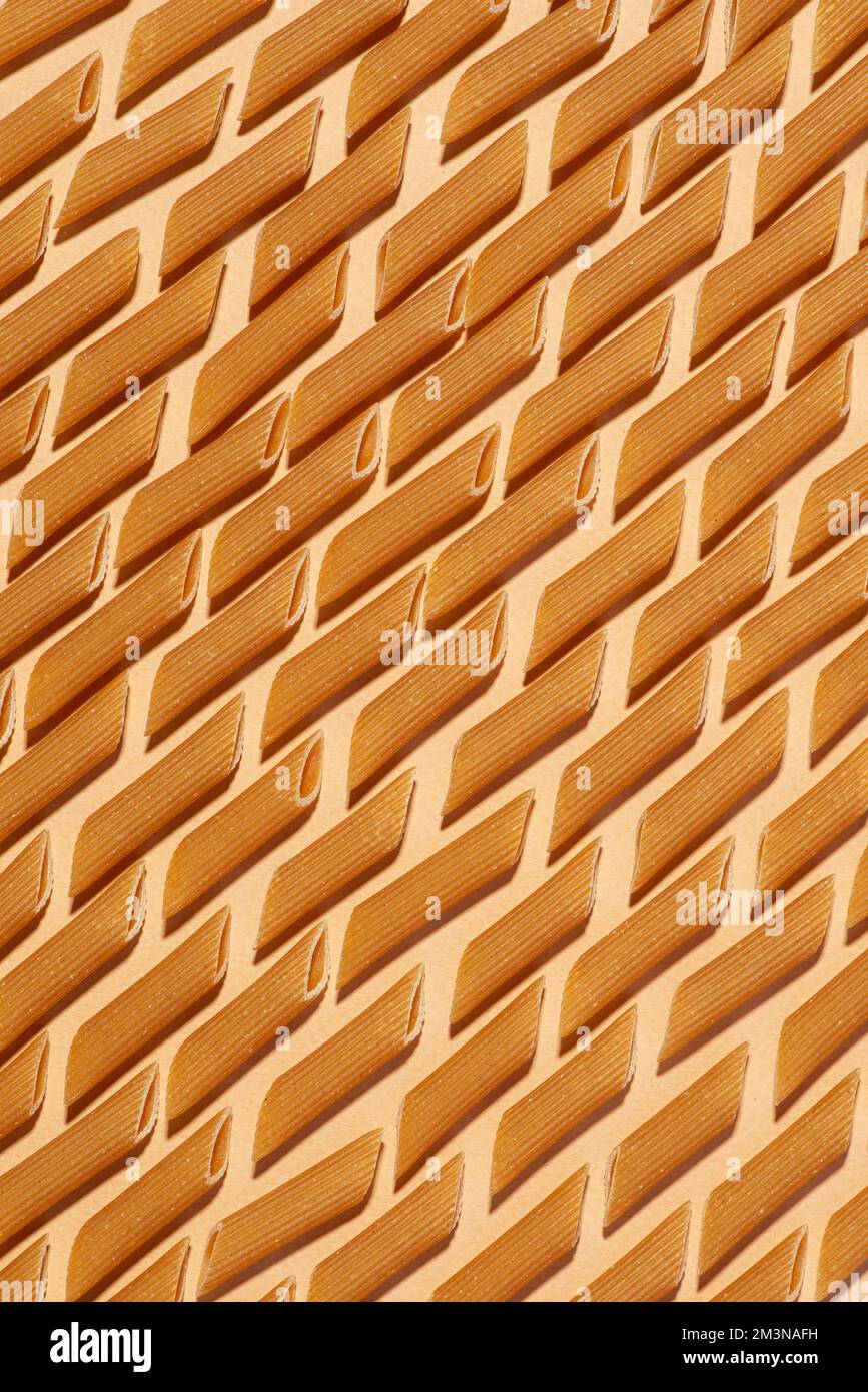 Pasta cruda di farina integrale su fondo beige. Ripetizione. Trama Foto Stock