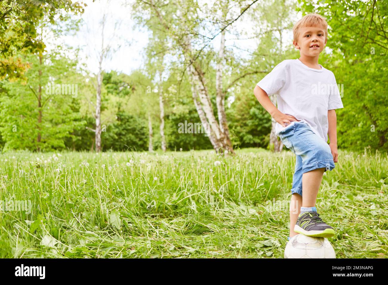 Ritratto del ragazzo in piedi sul calcio nel giardino verde durante le vacanze estive Foto Stock