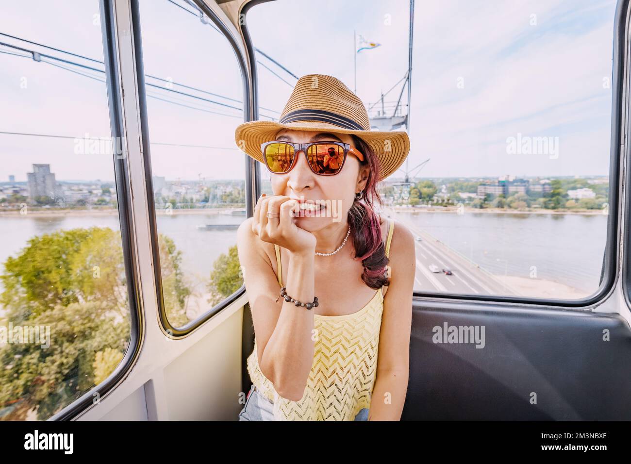 La ragazza sta sperimentando un attacco di panico a causa della paura di altezze e fobia. Incidente e guasto di una funivia Foto Stock