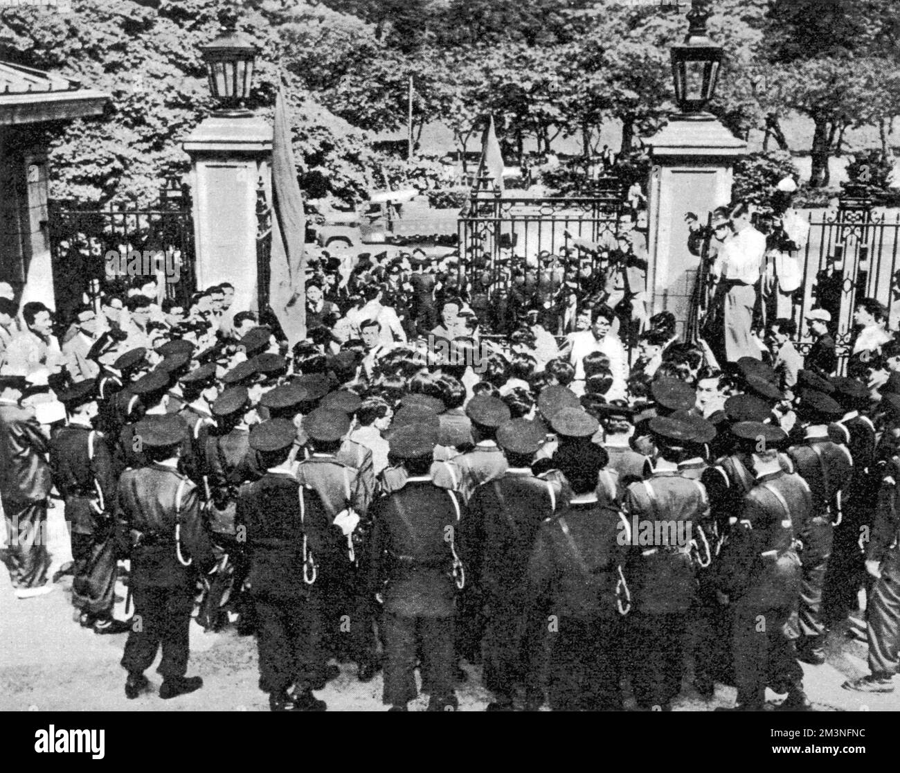 Tokyo, Giappone: Un piccolo gruppo di studenti giapponesi, completamente circondati dalla polizia, che dimostravano contro i test nucleari britannici. Il 16th 1957 maggio un gruppo di membri dell'Unione degli studenti di Tokyo si è disostrato fuori dalle porte dell'ambasciata britannica, portando con sé cartelli che recitavano "giù con Macmillan" e "protestiamo contro la bomba H britannica". Un gruppo più piccolo ha messo in scena una protesta di "sit down" nei terreni dell'ambasciata. Data: 16th maggio 1957 Foto Stock