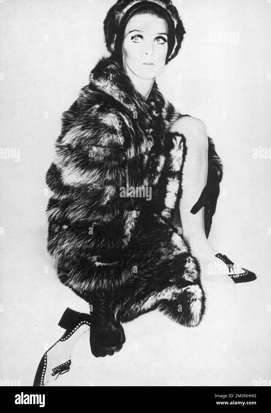 Lussuoso cappotto di opossum naturale con stretta cravatta in pelle scamosciata di Fab Furs, 72 guineas, indossato con un cappello abbinato e scarpe stile brogue. Data: 1966 Foto Stock