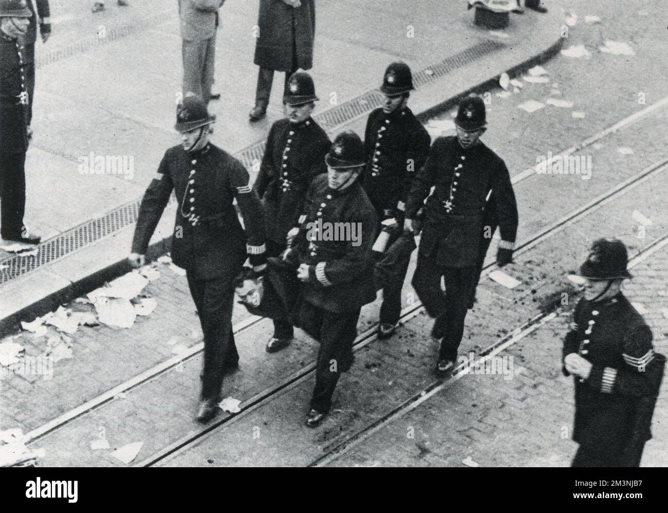 Un dimostratore è portato via da cinque poliziotti, uno dei 84 arresti effettuati durante la manifestazione antifascista nell'East End di Londra, in opposizione alla marcia proposta da Sir Oswald Mosley e dall'Unione britannica dei fascisti. Data: 4 ottobre 1936 Foto Stock