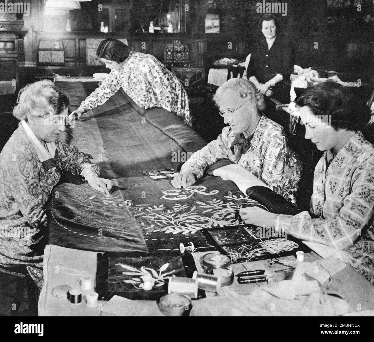 Le donne della Royal School of Needlework a Prince's Gate, Kensington, Londra, hanno visto lavorare sul vestito di incoronazione per la regina Elisabetta II Il vestito di seta pura è stato ricamato con un disegno scelto dalla Regina. Sulla sinistra del tavolo è Miss Violet Wise e sulla destra (più lontano dalla telecamera) è Miss. Evans, entrambi impegnati a lavorare sulle vesti di incoronazione per la Regina Madre nel 1937. Di fronte alla destra c'è Miss Bartlett. La scuola fu fondata dalla principessa cristiana (principessa Helena) nel 1872. Data: 1953 Foto Stock