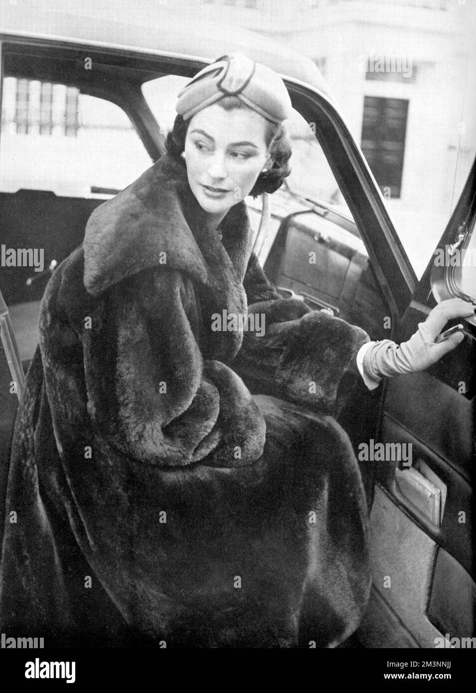 Un modello, vestito per lo shopping natalizio, indossa un cappotto di nutria a dorso di altalena di Molho di Brook Street. Data: 1953 Foto Stock