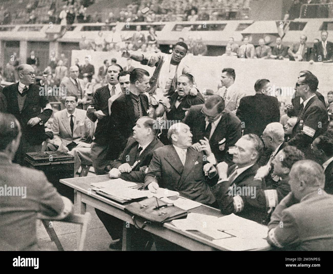 Basilio Alves dell'Uruguay è sopportato verso il rostro del giudice dal direttore uruguayano. Ci fu un tumulto all'Empire Pool dopo la sua sconfitta sui punti a mano dell'americano Eddie Johnson. Data: 1948 Foto Stock Basilio Alves dell'Uruguay è sopportato verso il rostro del giudice dal direttore uruguayano. Ci fu un tumulto all'Empire Pool dopo la sua sconfitta sui punti a mano dell'americano Eddie Johnson. Data: 1948 Foto Stock