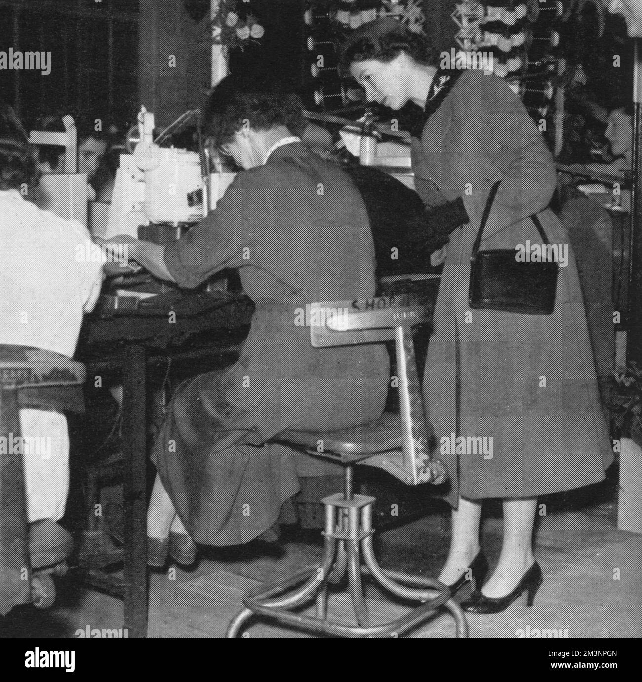 La Regina guarda più da vicino i lavori in corso in una delle panchine della fabbrica John Lucas di Birmingham. Data: 1955 Foto Stock