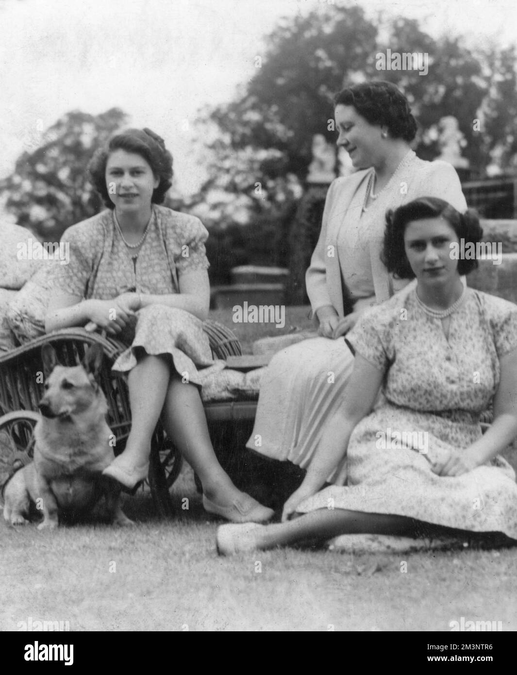La principessa Elisabetta (poi regina Elisabetta II) e la principessa Margherita siedero insieme alla loro madre, la regina Elisabetta e un corgi. Data: c.1945 Foto Stock