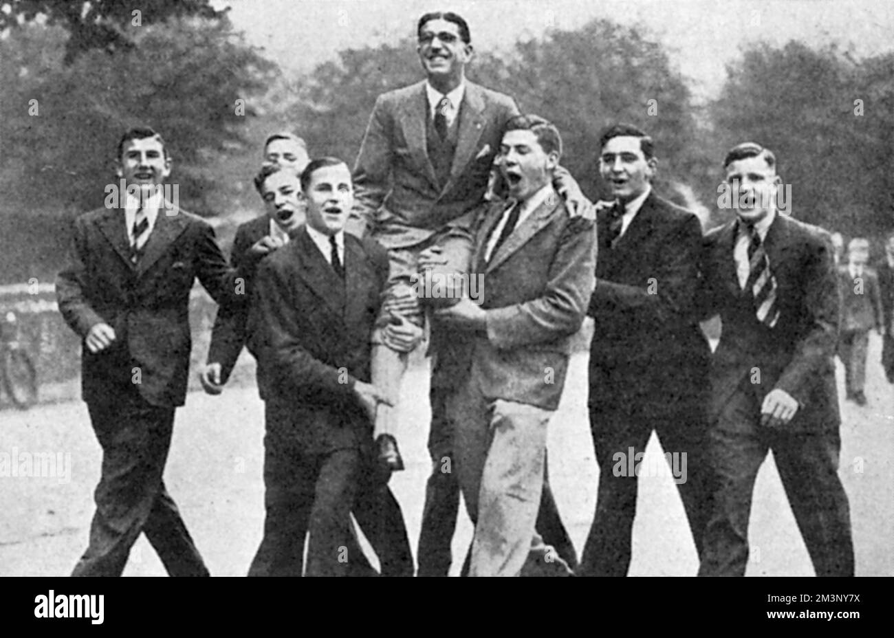 Thomas "Tommy" Hampson (1907 1965), atleta britannico, vincitore dei 800 metri alle Olimpiadi estive di Los Angeles del 1932, raffigurato sulle spalle dei ragazzi di St. Alban's School dove era un insegnante. Data: 1932 Foto Stock