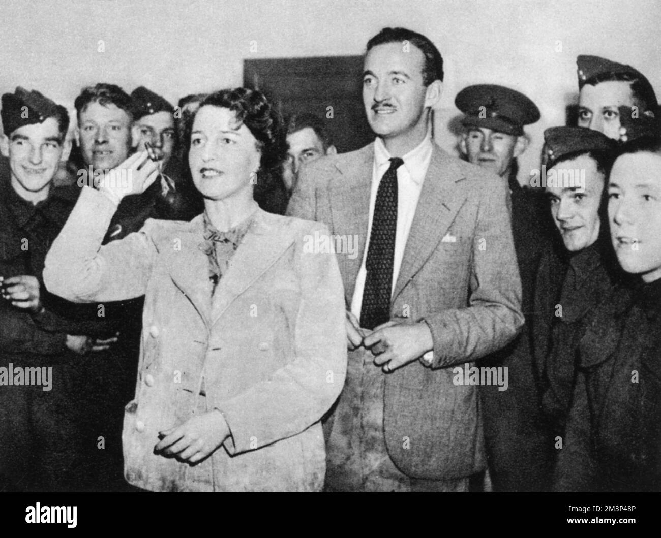 La signora Ronald Tree e l'attore David Niven a un concorso di freccette in una mensa. Nancy Lancaster (Nee Perkins, 1897 – 1994) è stato un . Sposò Ronald Tree nel 1920, trasferendosi in Gran Bretagna nel 1927; la coppia divorziò nel 1947 e sposò Claude Lancaster nel 1948. È stata associata con lo stile inglese della Country House. Data: 1939 Foto Stock