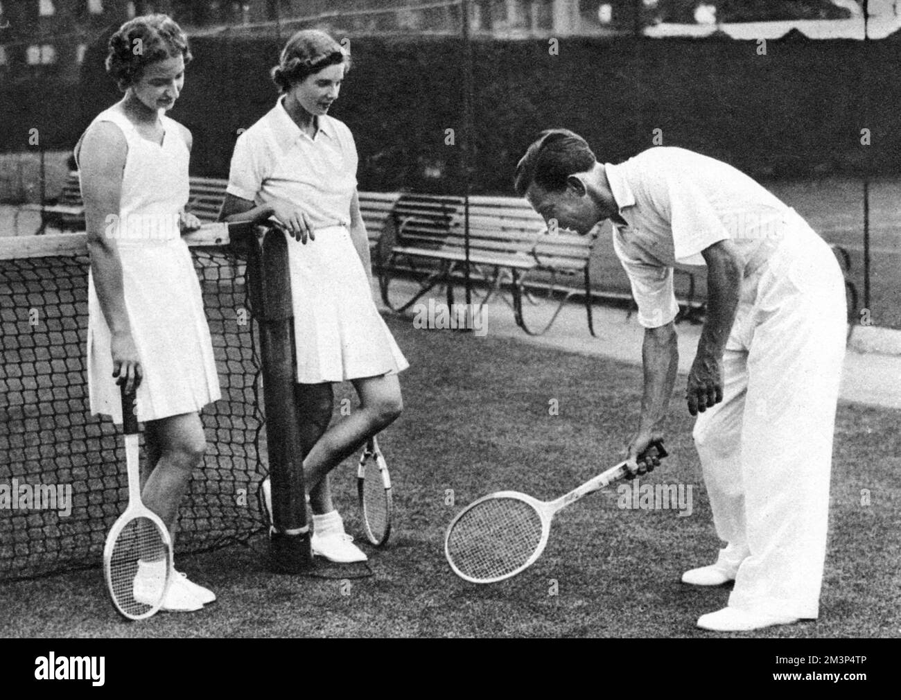 DaN Maskell (1908 - 1992), tennista britannico, allenatore e poi amava universalmente Wimbledon commentatore. Foto che mostra alle Miss Mary Hardwick e alle Miss Kay Stammers il metodo corretto per distribuire un mezzo-volley. Data: 1937 Foto Stock