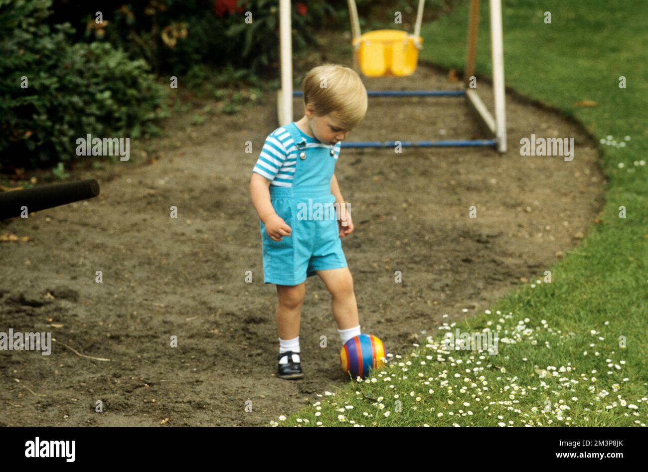 Principe William, Duca di Cambridge (1982-presente), qui raffigurato come un bambino di età compresa tra i tre e i quattro anni, che gioca in giardino con una palla Data: 1985 Foto Stock